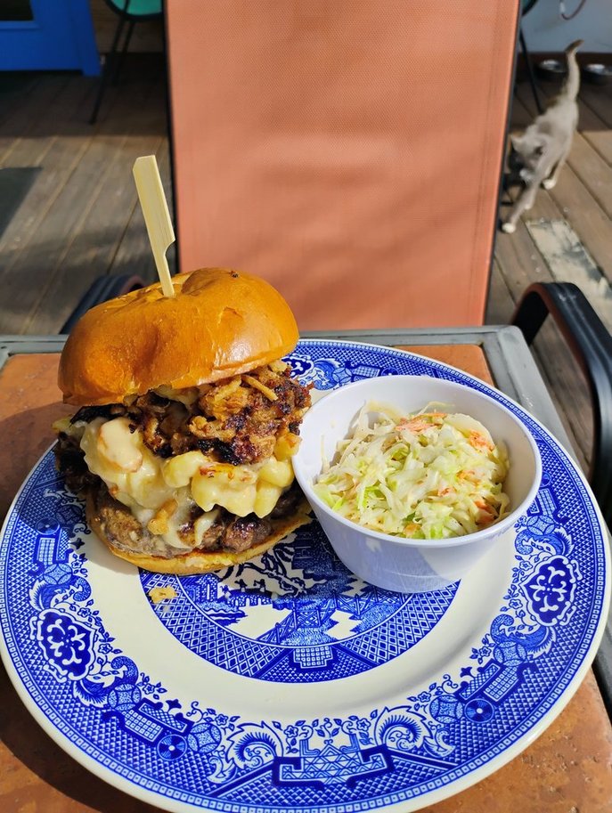 The Big Back Mac, February 2026 Burger of the Month, topped with boozy mac and cheese, pulled pork, whiskey BBQ sauce, and onion tanglers