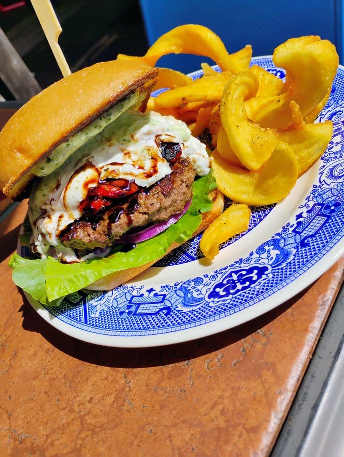 The Caprese, April 2026 Burger of the Month, with burrata, oven roasted tomatoes, balsamic glaze, and basil aioli on a ciabatta roll